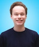 Portrait picture of Yummygum team member Guido  against a light blue backdrop while wearing a navy blue sweater.