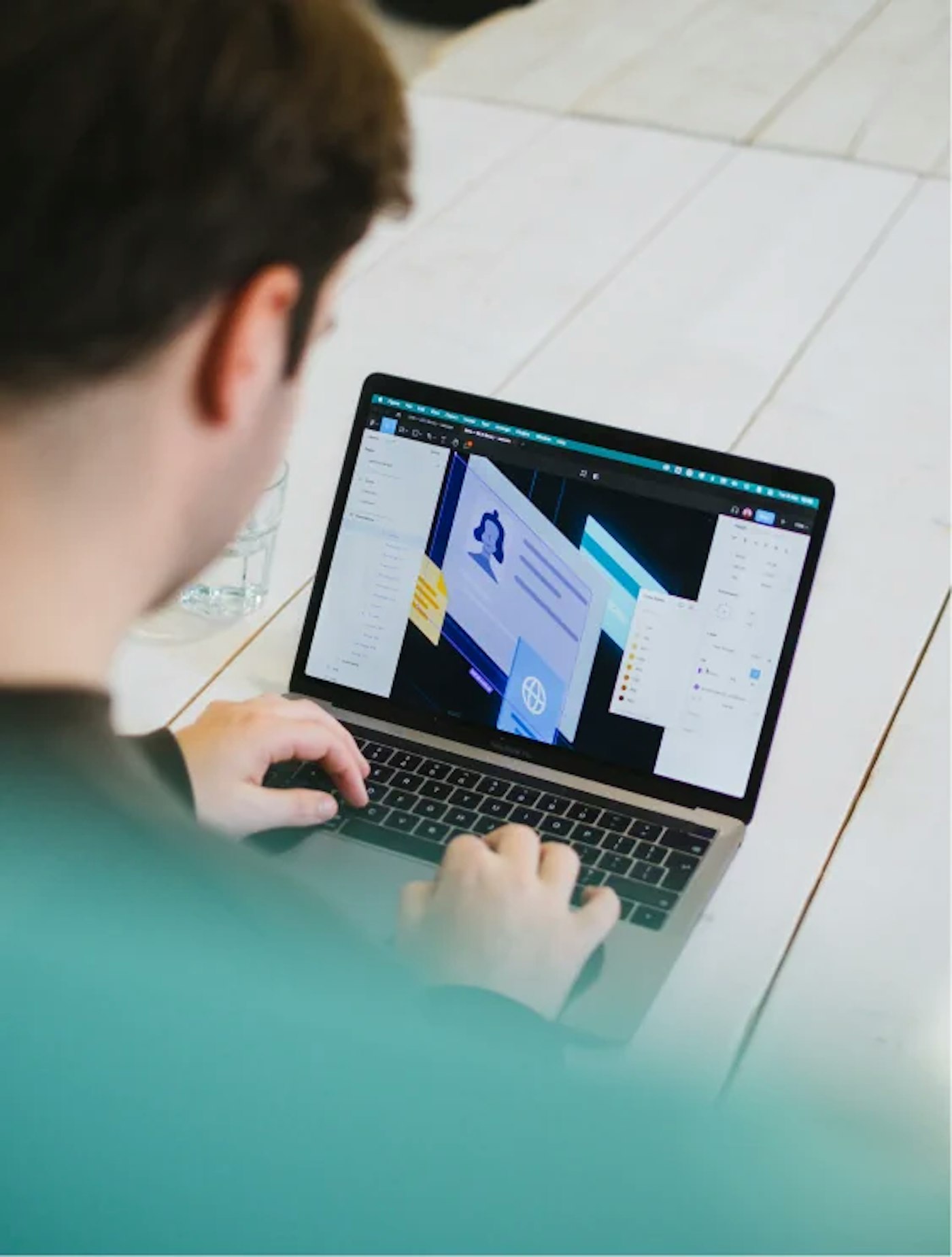 Person working as seen over their shoulder, working on a laptop that shows a design tool as they're working on an illustration.