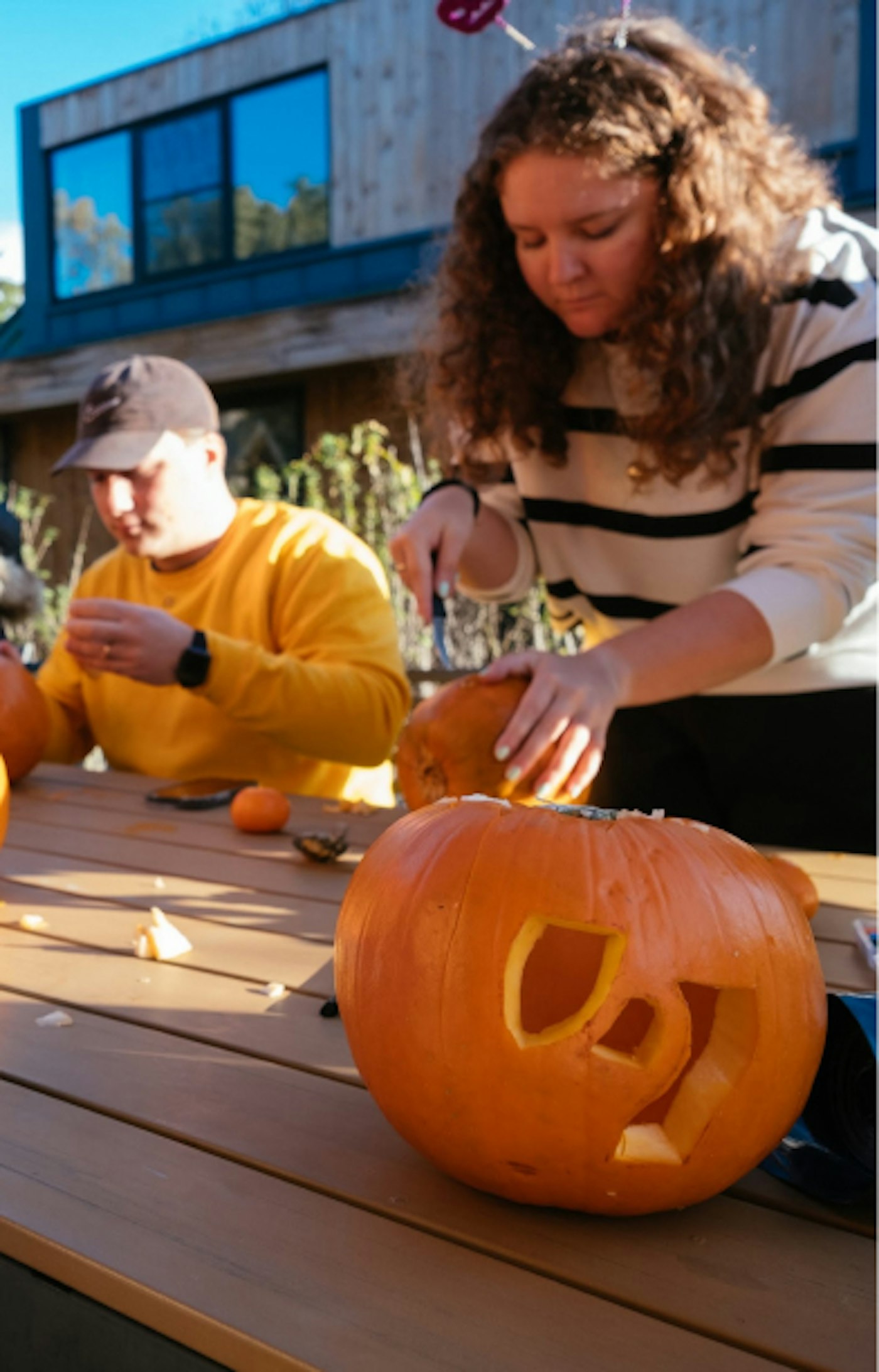People carving Halloween pumpkins. One pumpkin has the Yummygum logo mark carved out.