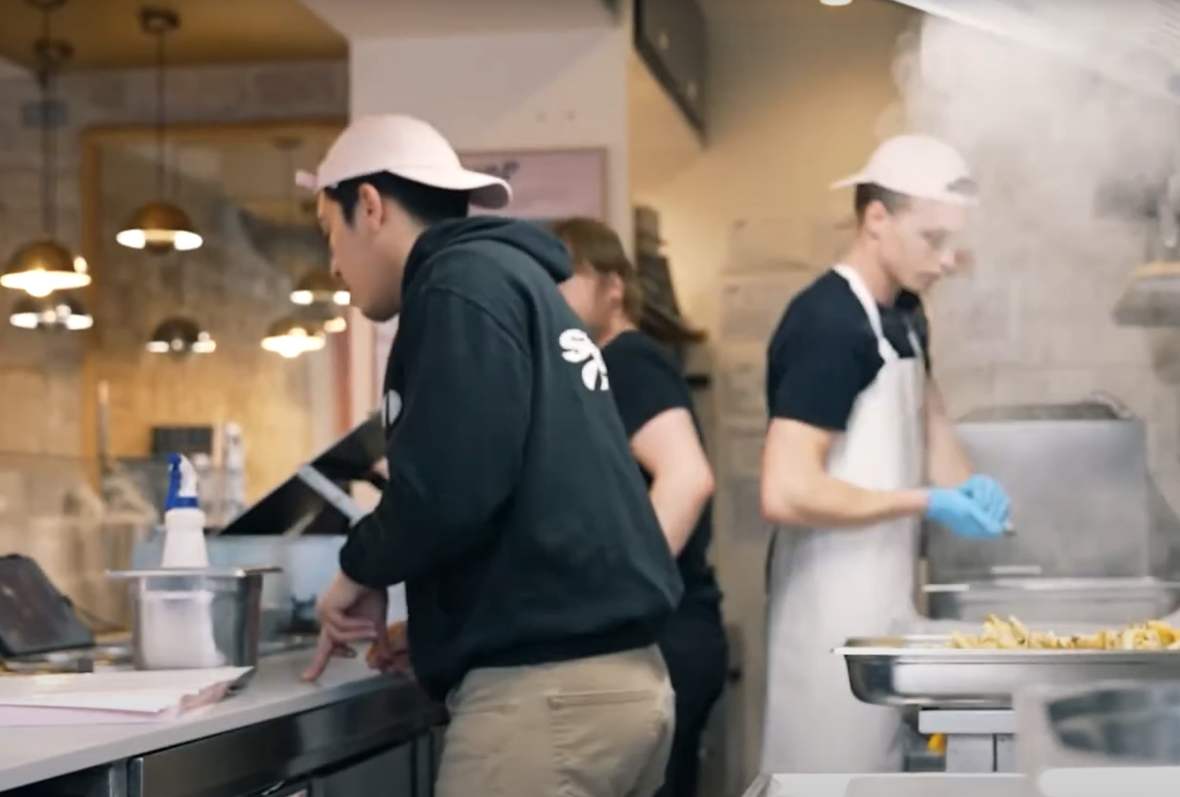 Photo de cuisiniers en train de préparer des burgers en cuisine.
