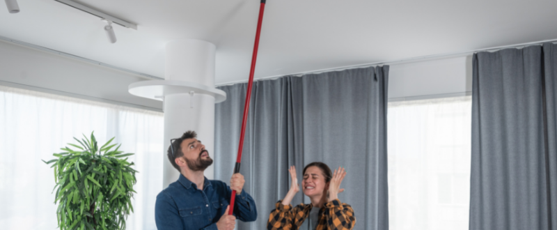 Couple hitting broom on the cieling