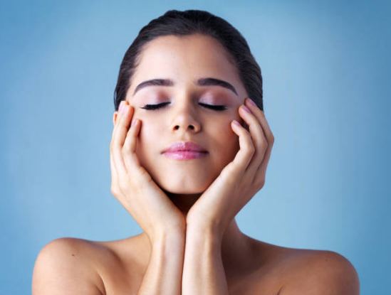 close up of brunette model with hands on face