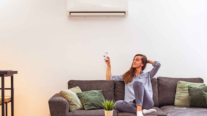 woman on couch holding airconditioning remote