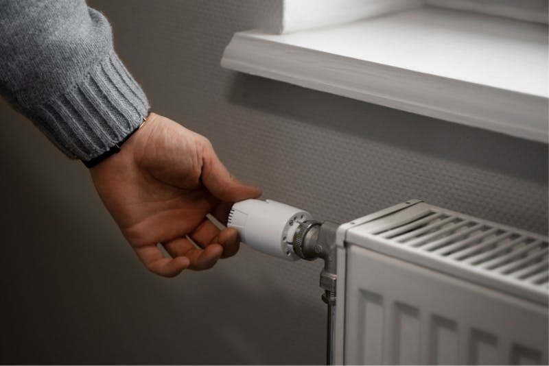 Man turning knob of radiator