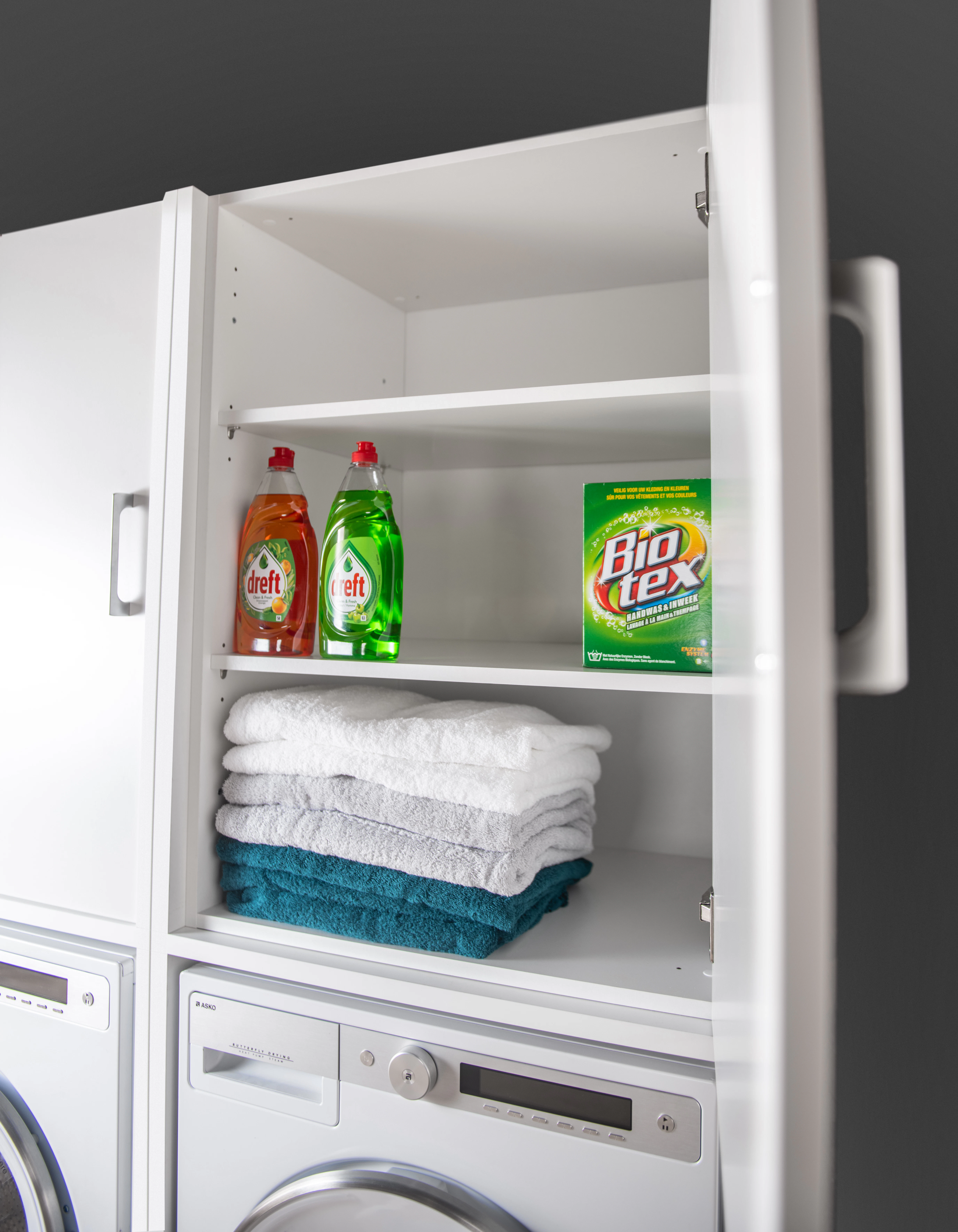 Open view of top cupboard with laundry detergents and towels