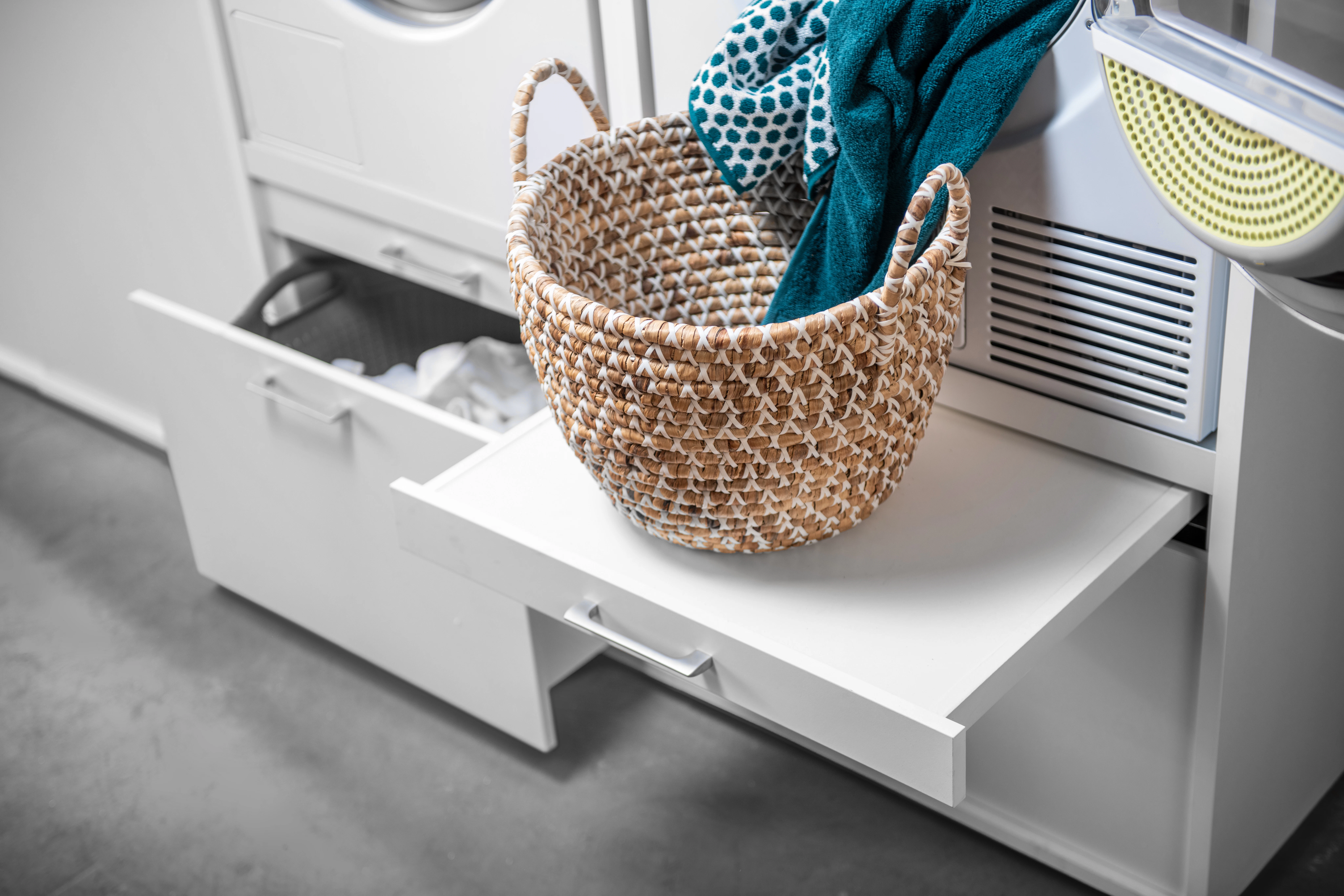 Lifestyle picture of white pull out table-drawer with basket of towels