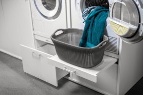 Weißer Schrank für Waschmaschine und Trockner mit praktischer Ausziehplatte für den Wäschekorb