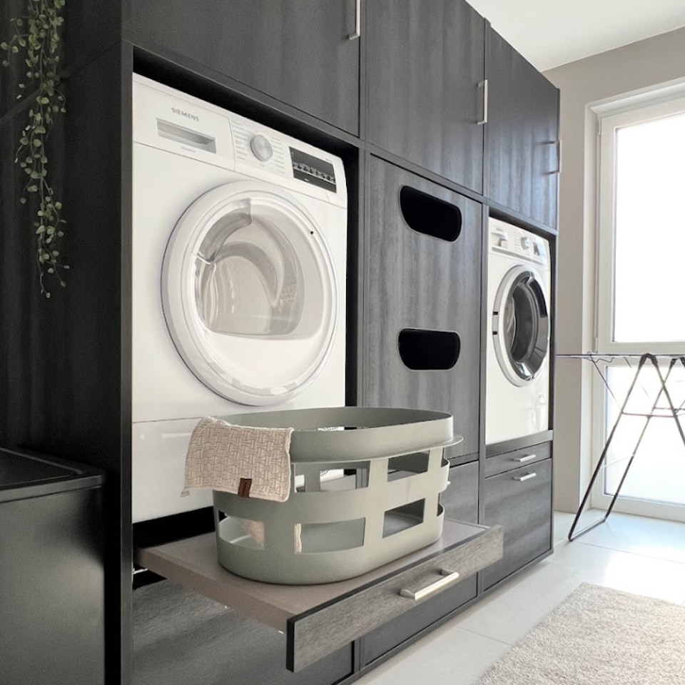 eine schwarze Schrankwand als Idee für Waschraum mit erhöhten Schränken für Waschmaschine und Trockner