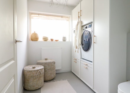 Voorbeeld  van wasruimte met wasmachine en droger naast elkaar in witte kast