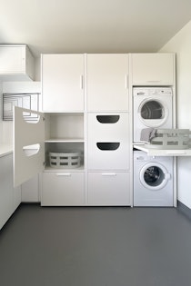 schwarzer Schrank mit Wäscheeinwurf und Waschmaschine und Trockner übereinander