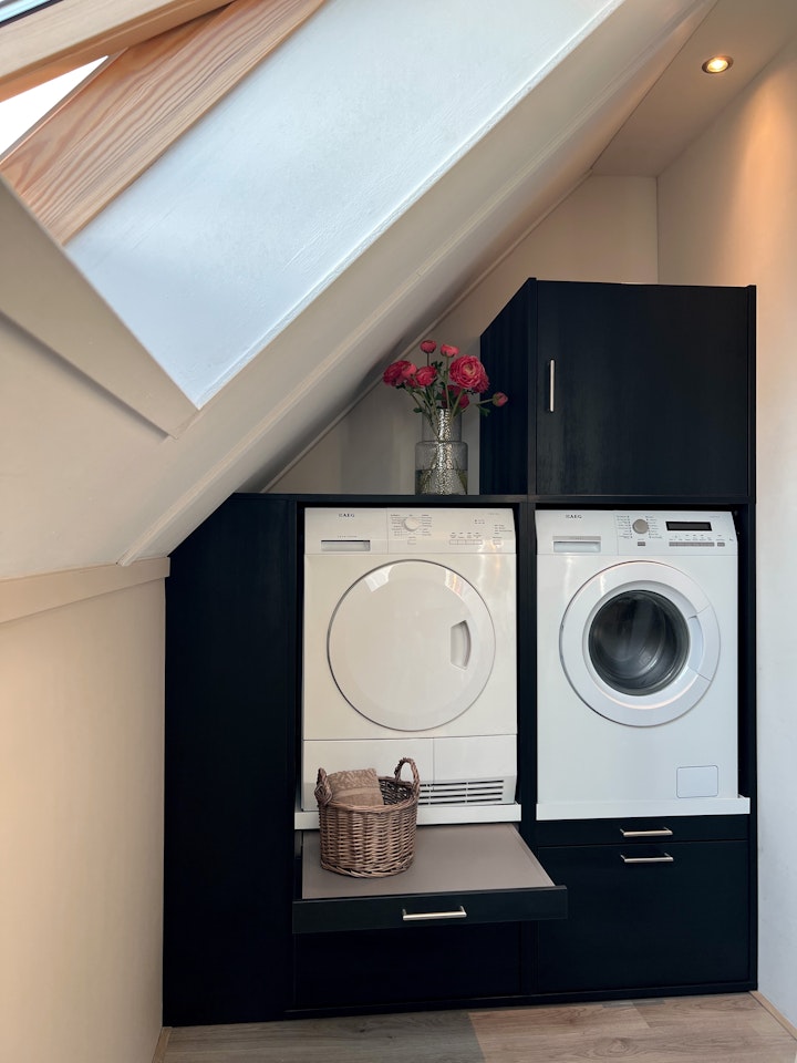 schwarzer Schrank für Waschmaschine und Trockner nebeneinanderin einer Dachschrägen als Ispiration