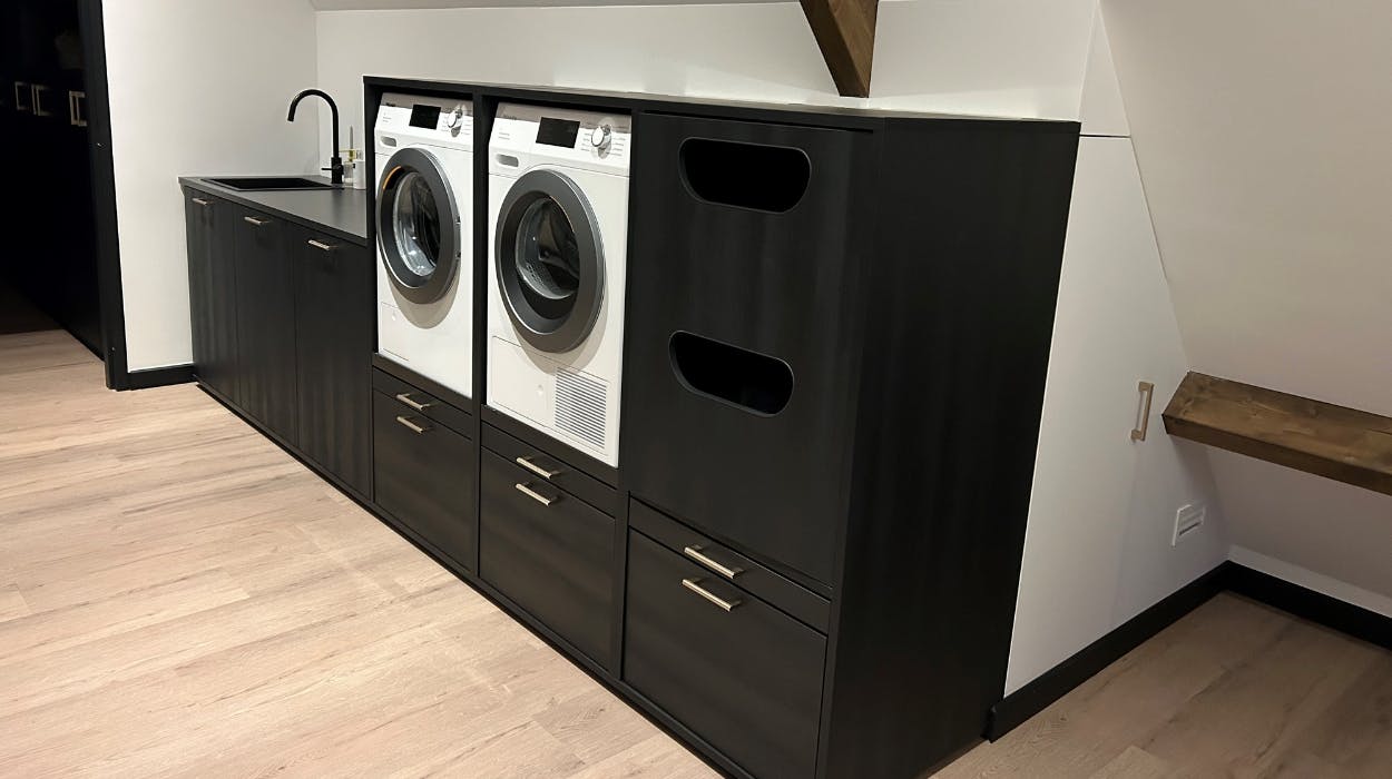 Idee für schwarze Schrankwand mit Waschmaschine und Trockner nebeneinander und Unterschränken integriert