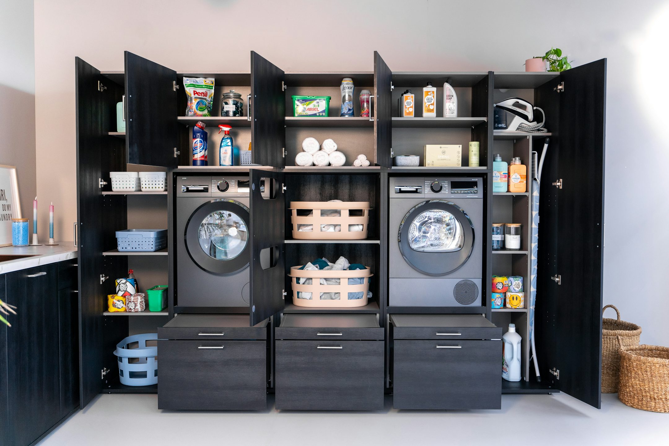 Schwarze Schrankwand mit optimalen Stauraum im Hauswirtschaftsraum. Ordnung und Integration durch Waschturm