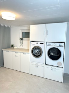 Waschküche im Keller weißer Schrank mit zusätzlichen Unterschränken und Arbeitsplatte