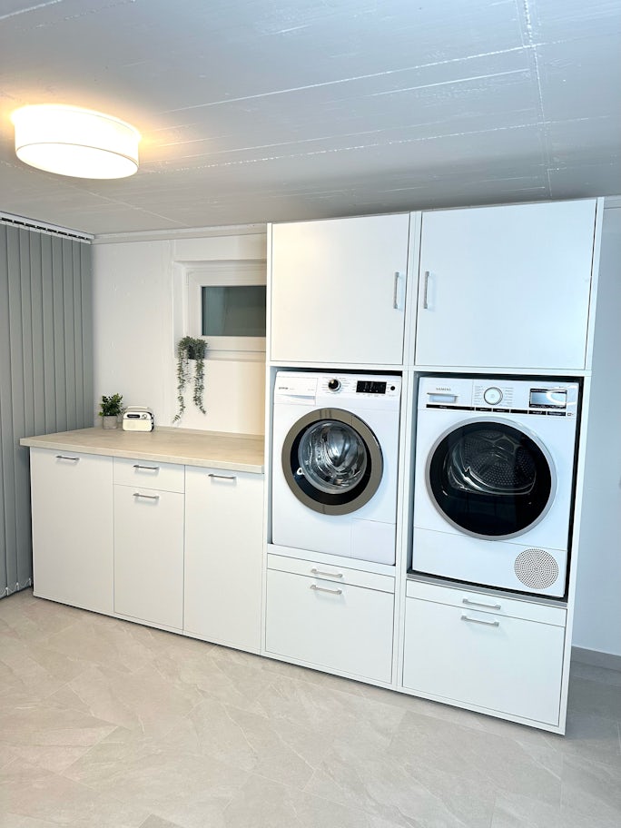 Waschküche im Keller weißer Schrank mit zusätzlichen Unterschränken und Arbeitsplatte