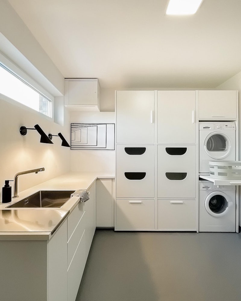 Wastoren bijkeuken idee ter inspiratie voor de inrichting van een bijkeuken met wasmachine en droger op elkaar. Gecombineerd met keuken blok, gootsteen, aanrechtblad en speciale korflades voor de wasmand.