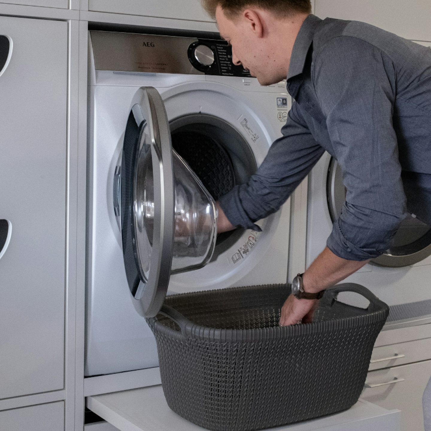 Ein erhöhter weißer Schrank für die Waschmaschine mit Ausziehplatte für Wäschekorb. Waschturm Inspiration Ideen