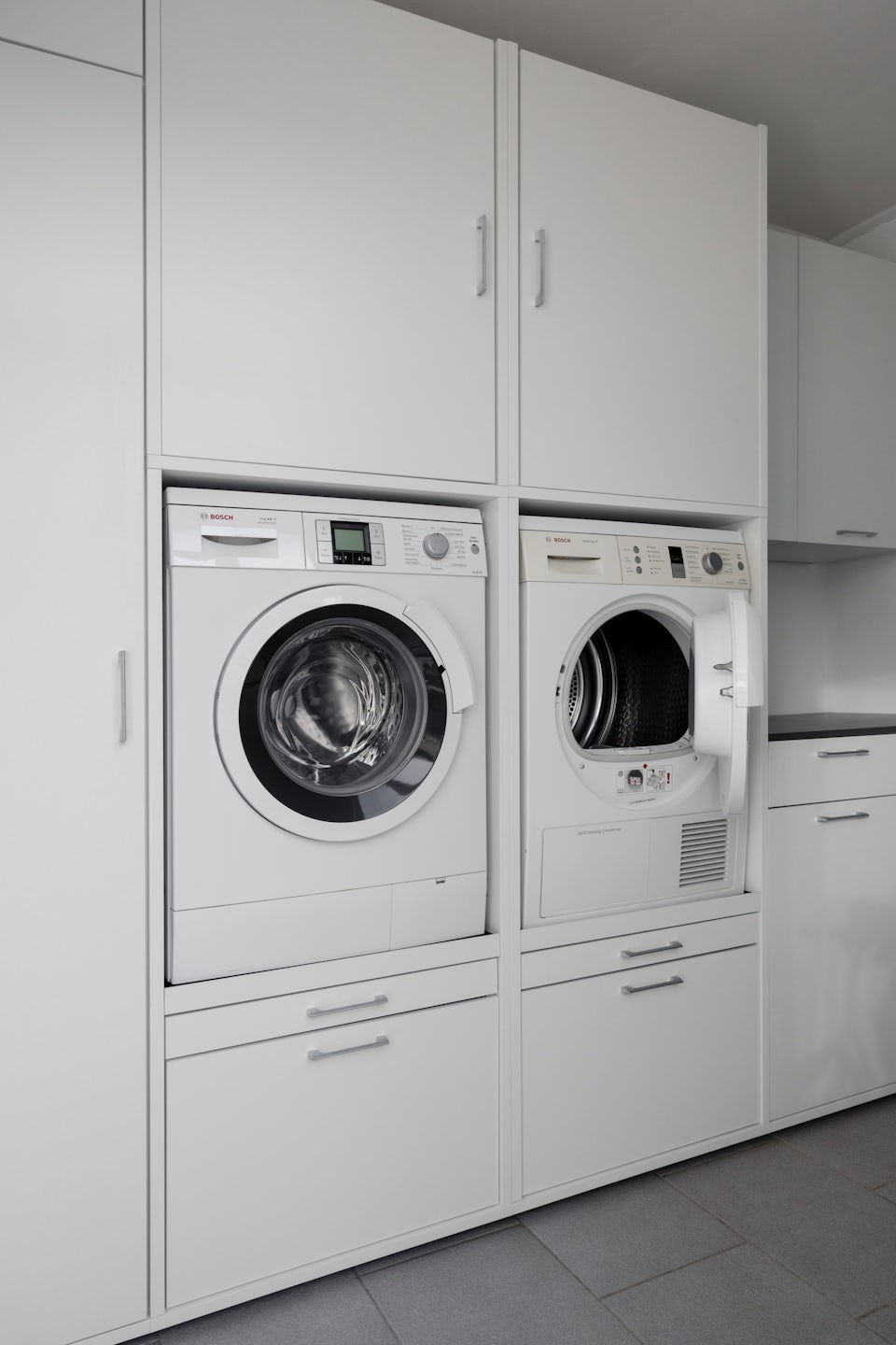 dubbele wasmachine verhoger voor wasmachine en droogkast naast elkaar bijkeuken wit inspiratie ideeen met opbergkasten voor wasprodcuten interieur