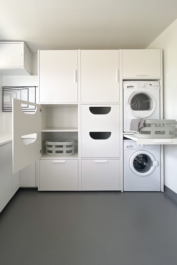 wasmachine ombouw bijkeuken met droogkast op de wasmachine gestapeld met uittrekplateau voor wasmand en inzetstuk voor wasmand en opberkasten voor wasproducten in het wit ingebouwd met keukenblad keukenblok