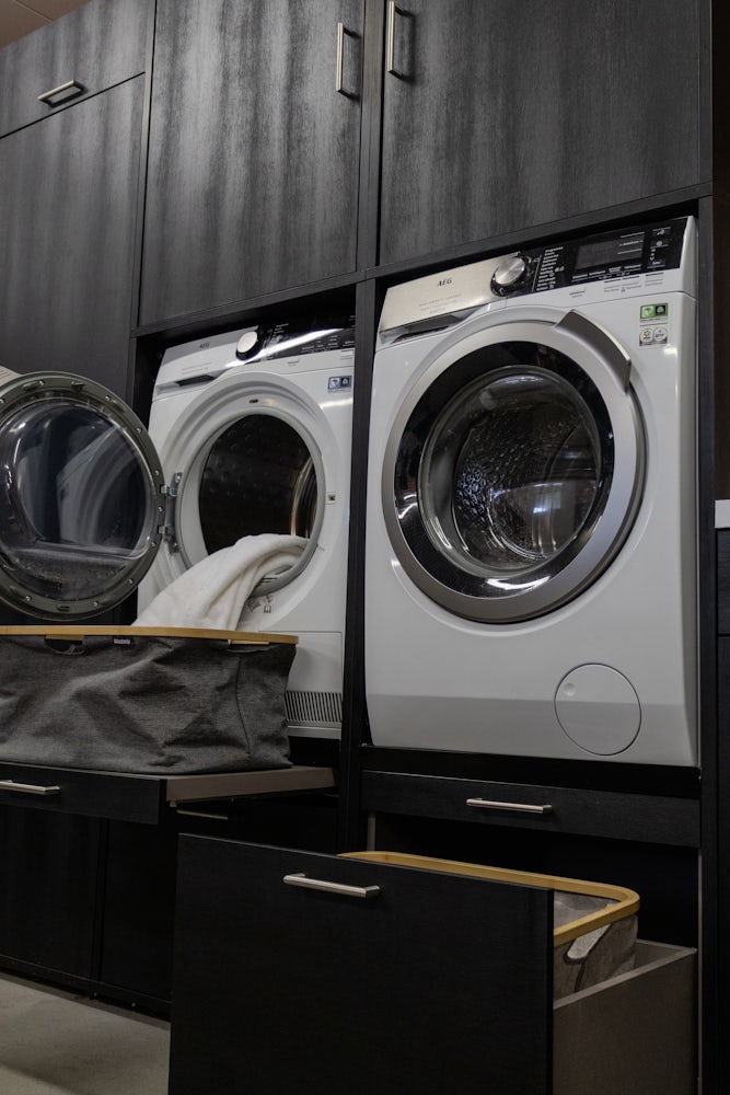 Wastoren dubbele waskast zwart met wasmachine en droger naast elkaar en met een uittrekplateau voor wasmand en korflade voor wasmand met opbergkasten en verhoger 60 centimeter