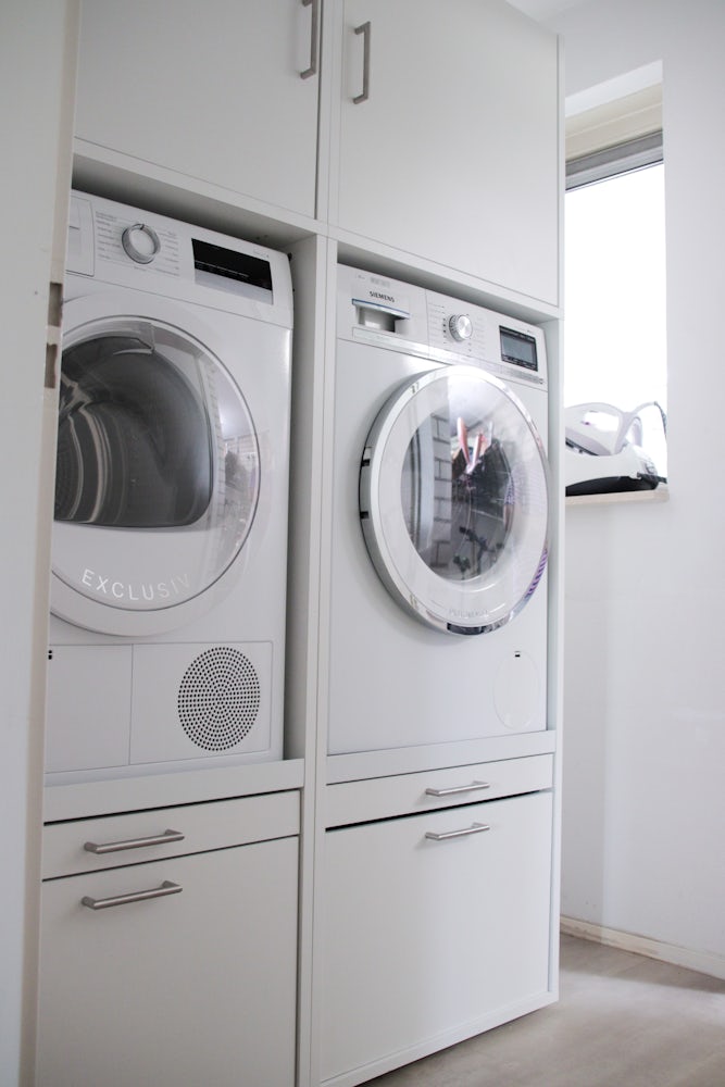 Wastoren wasmachine kast wit inspiratie idee interieur met wasmachine en droger naast elkaar en uittrekplateau voor de wasmand en korflade eronder. Ook is de kast voorzien van bovenkasten. Geef je wasruimte een upgrade!