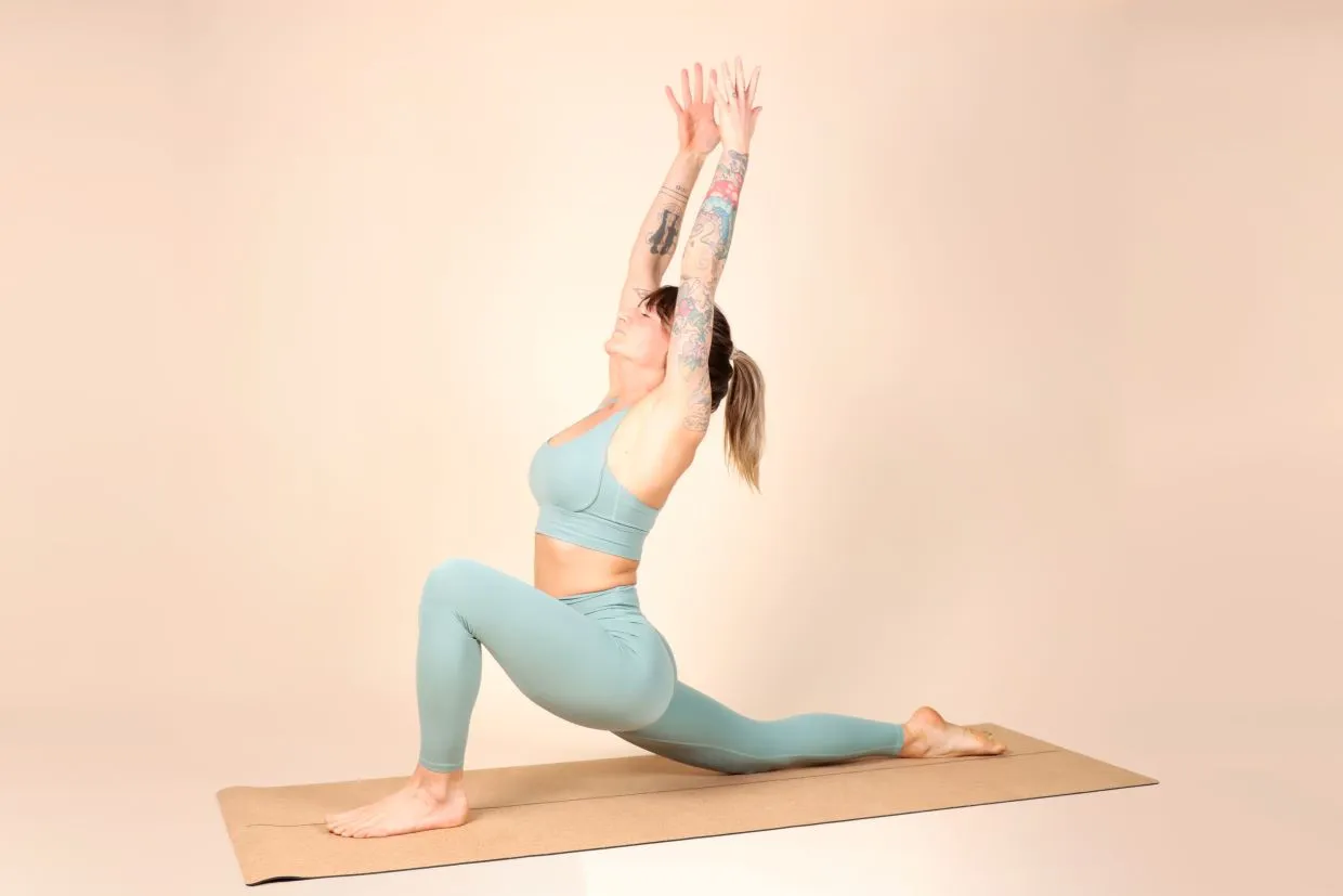 A woman standing on a yoga mat from Flowlife in the yoga position low lunge.