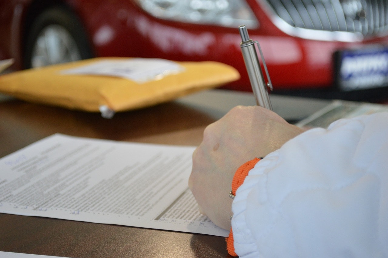 Foto di una mano che stringe una penna e firma documento
