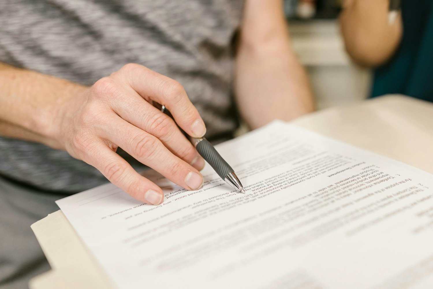 Foto di mano che tiene una penna mentre legge un documento