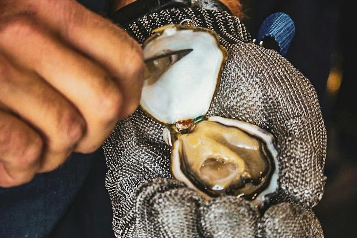 Dettaglio mano che apre un'ostrica Oyster Oasis