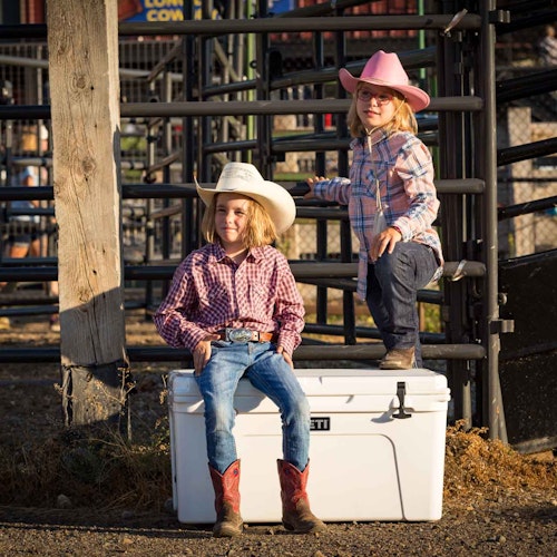 Little girls posing on a YETI cooler at the rodeo