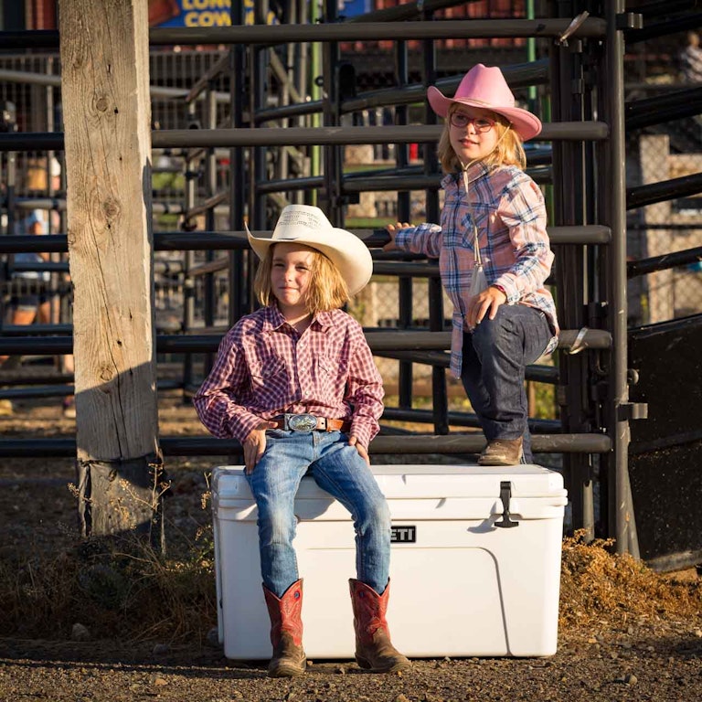 Two girls posing on a YETI cooler at the Rodeo