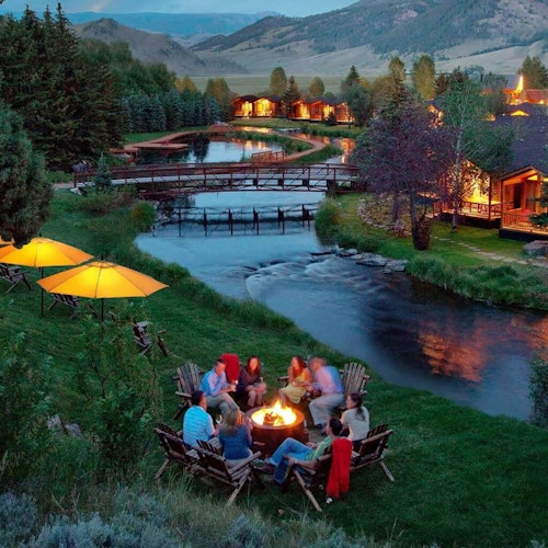 People sitting around a fire admiring the stream at the Rustic Inn