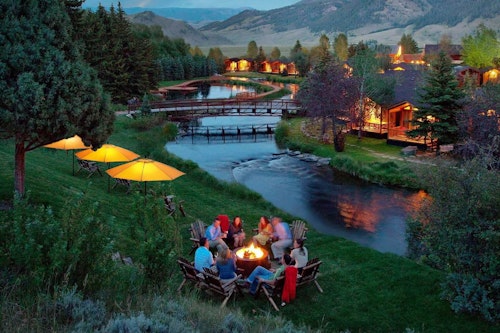 People sitting around a fire admiring the stream at the Rustic Inn