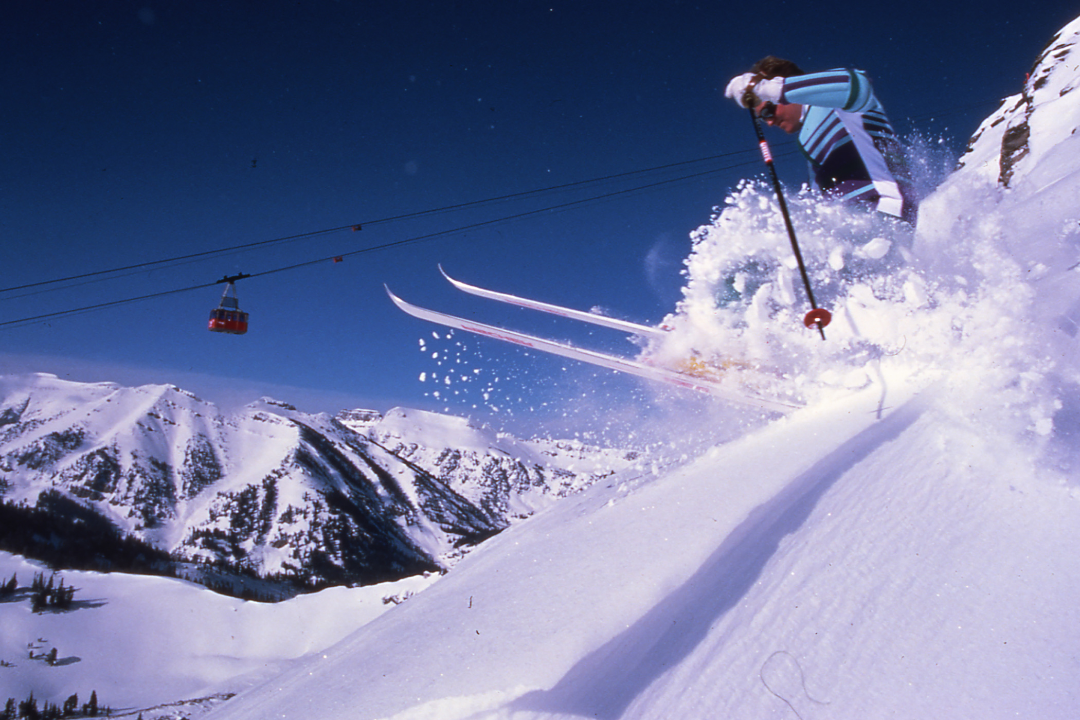 Vintage skier going down Rendezvous bowl with Tram in the background