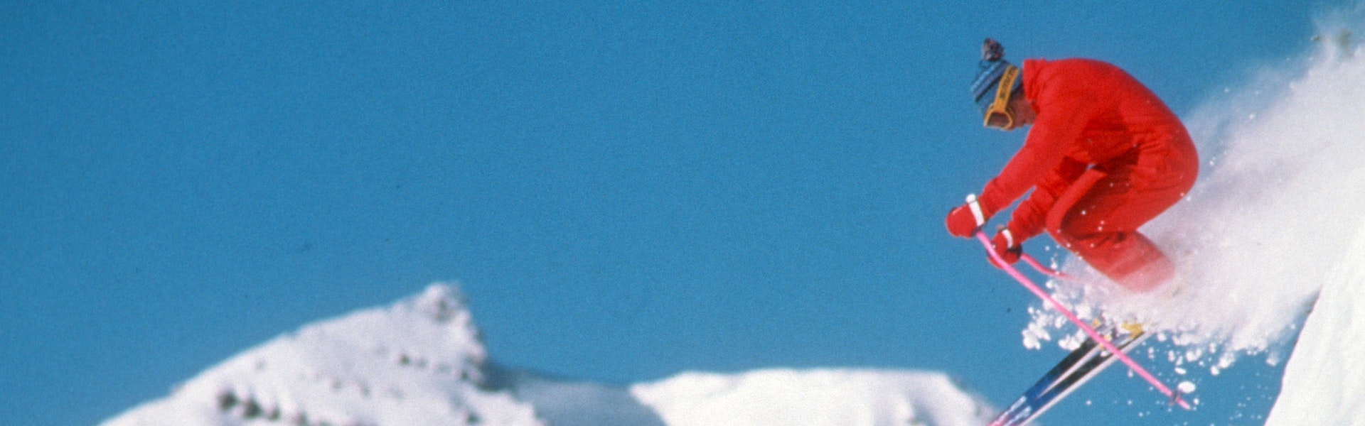 Vintage skier going down Rendezvous bowl with Tram in the background