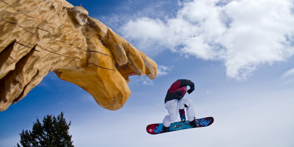 Snowboarder going off of a log rail