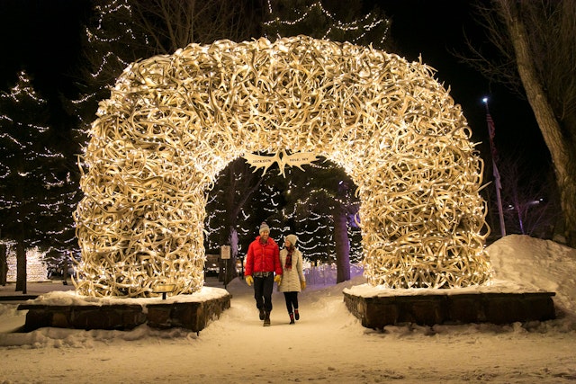 Couple walking under the antler arches on Town Square