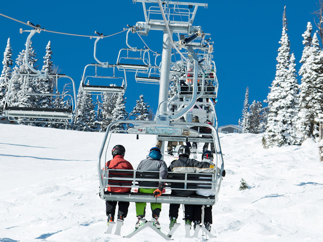 People riding up Teton chairlift on a sunny day