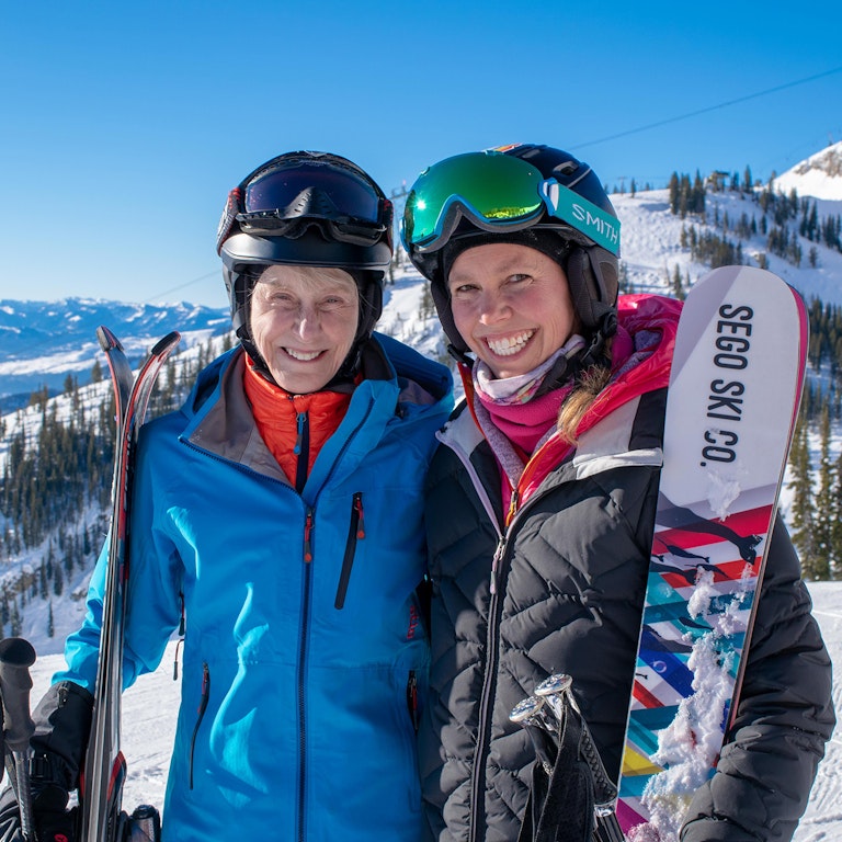 Two skiers smiling at the top of a run