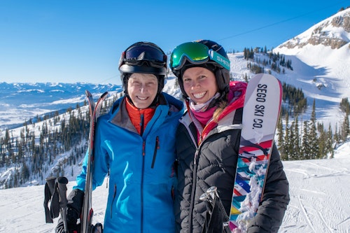 Two skiers smiling at the top of a run