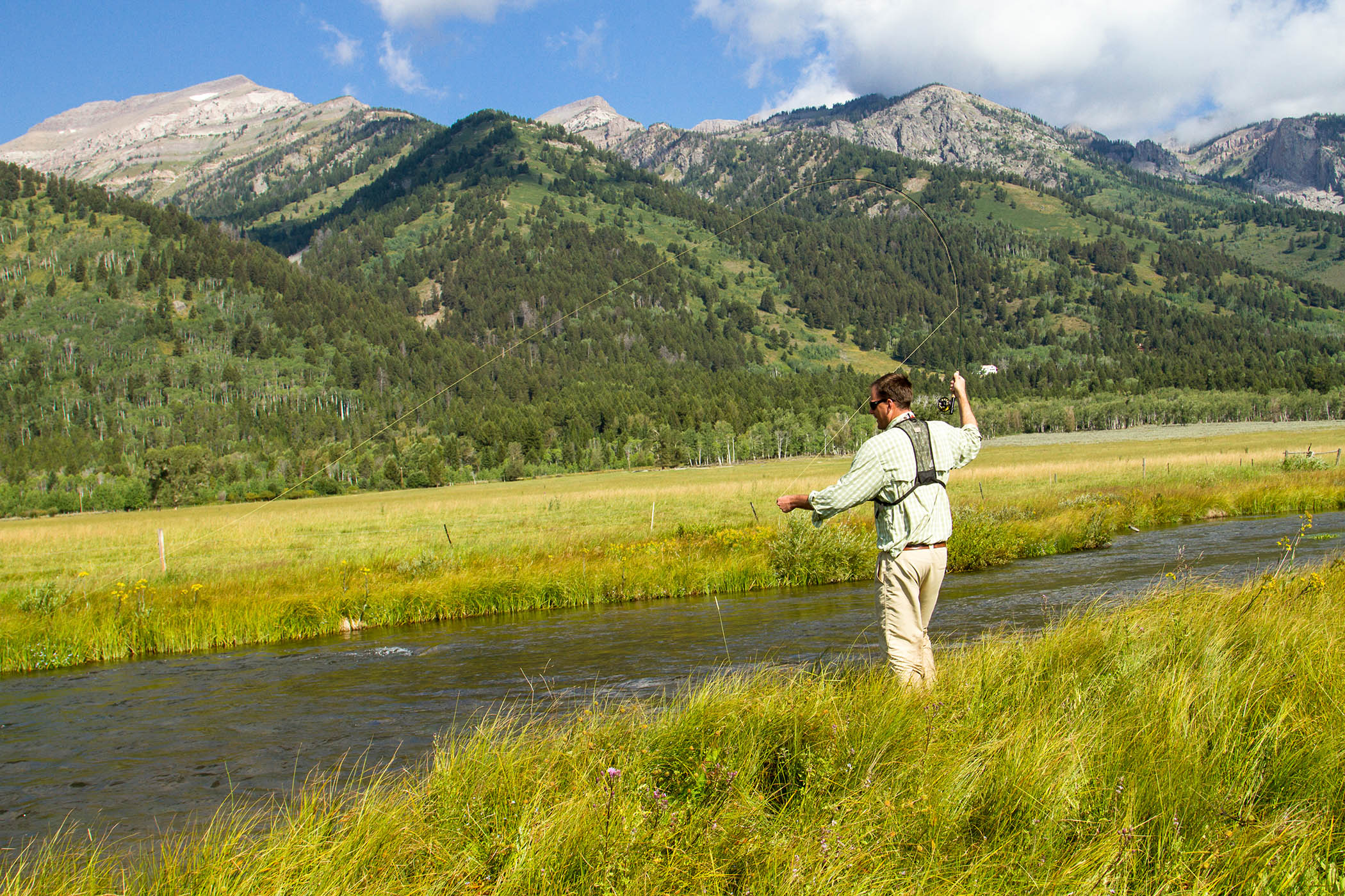 Fly fishing along Fish Creek against the mountains