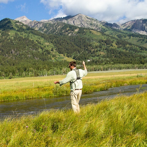 Fly fishing along Fish Creek against the mountains