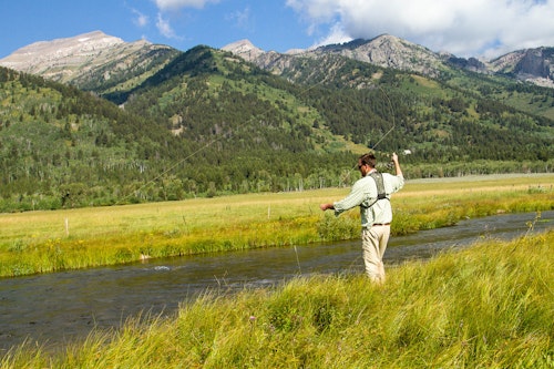Fly fishing along Fish Creek against the mountains