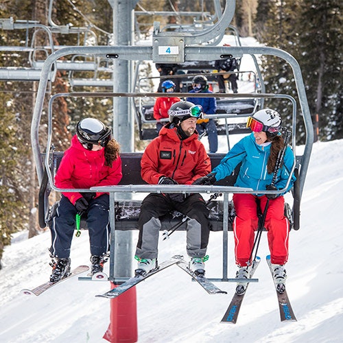 Adult students talking with ski instructor on chairlift