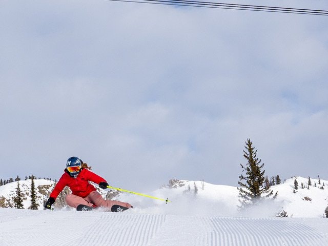 Women skiing down a groomer fast