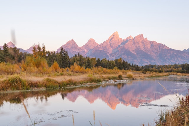Beautiful shot of the lake reflecting the Tetons with a pink sunset