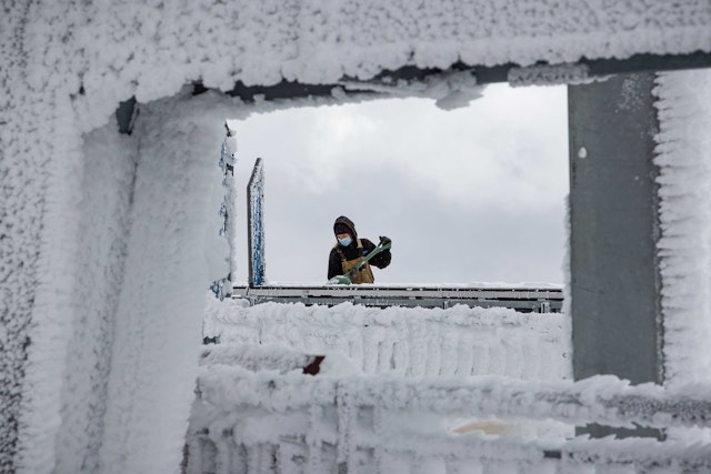 Tram operator knocking snow and ice off of railing on Tram dock