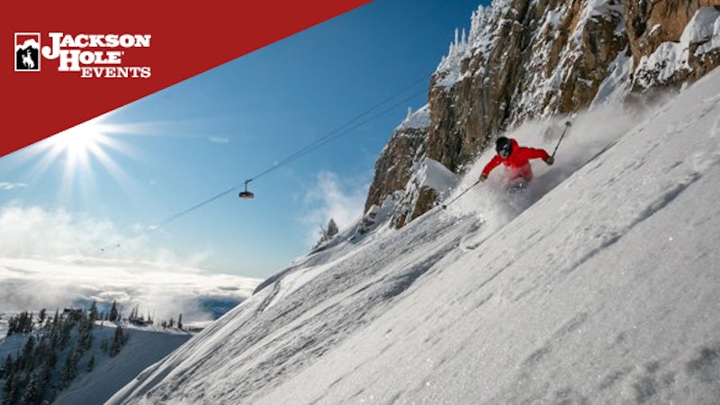 Skier going through deep powder with the Tram flying by in the background