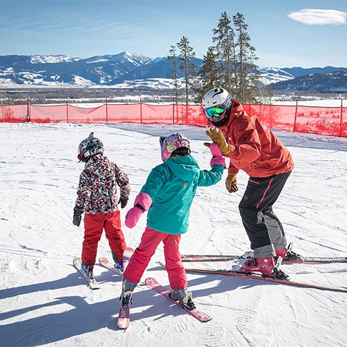 Ski instructor high-fiving their student