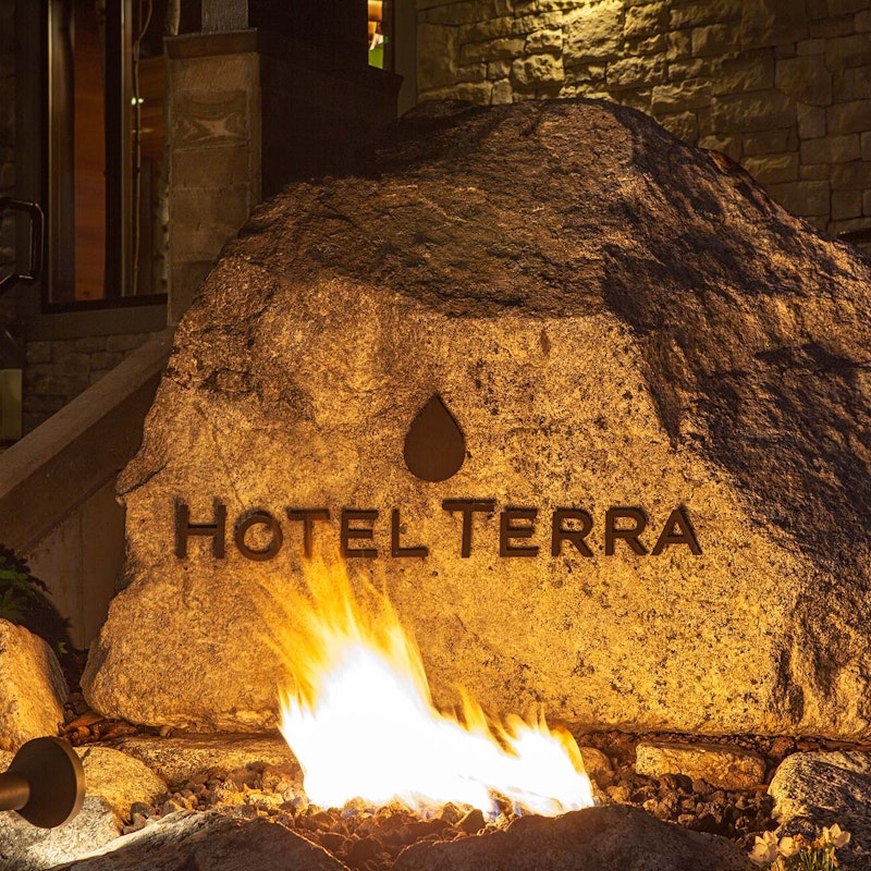 Rock that says "Hotel Terra" with fire in front